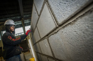 BAC apprentice strikes mortar joint on a block mockup at the International Training Center