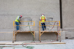 Craftworkers perform shotcrete on mobile scaffold at Unity Temple