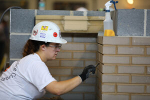 Woman craftworker repoints brick