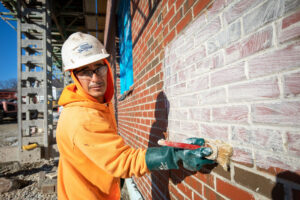 craftworker uses a brush to apply German schmear to the red brick masonry.