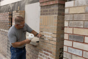 BAC instructor demonstrates removing grout from brick wall.